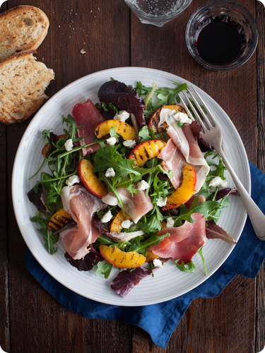 Plate of grilled peach and prosciutto salad